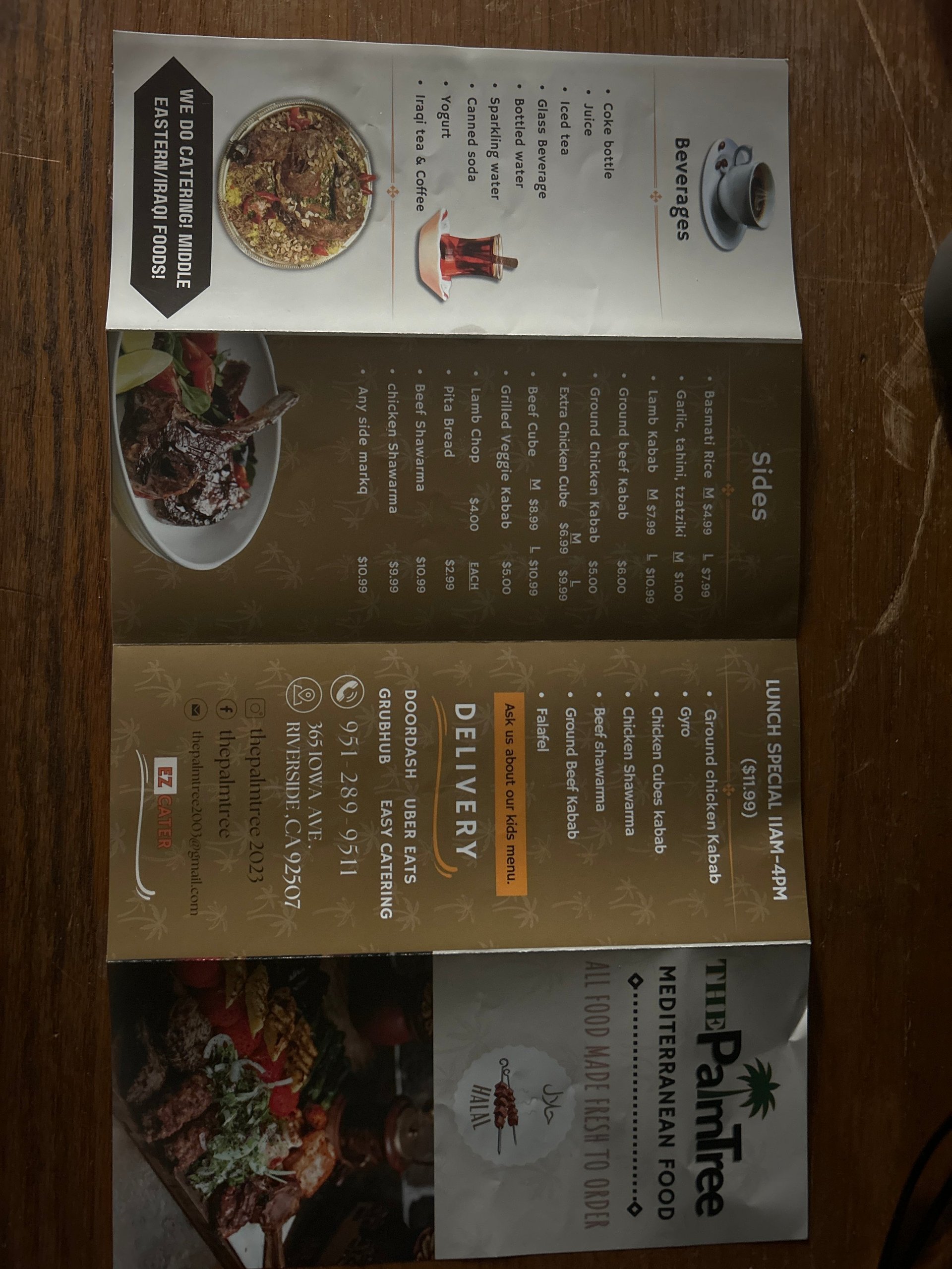 Multiple restaurant menus and takeout materials laid on a wooden table, including specialty cuisine options and drink selections
